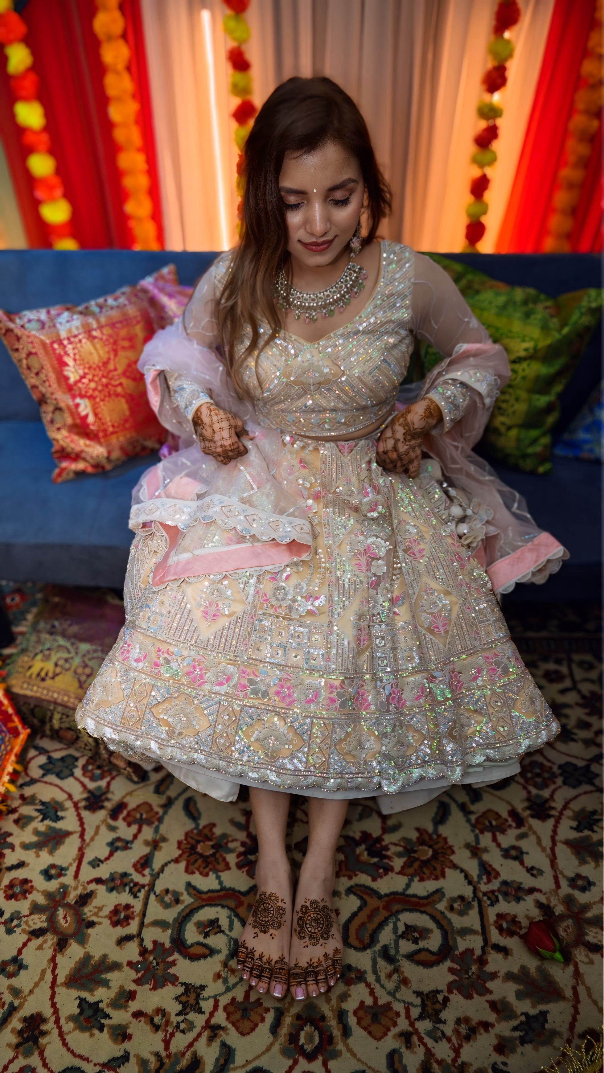 Bride with bridesmaids under mehndi neon sign at colorful celebration